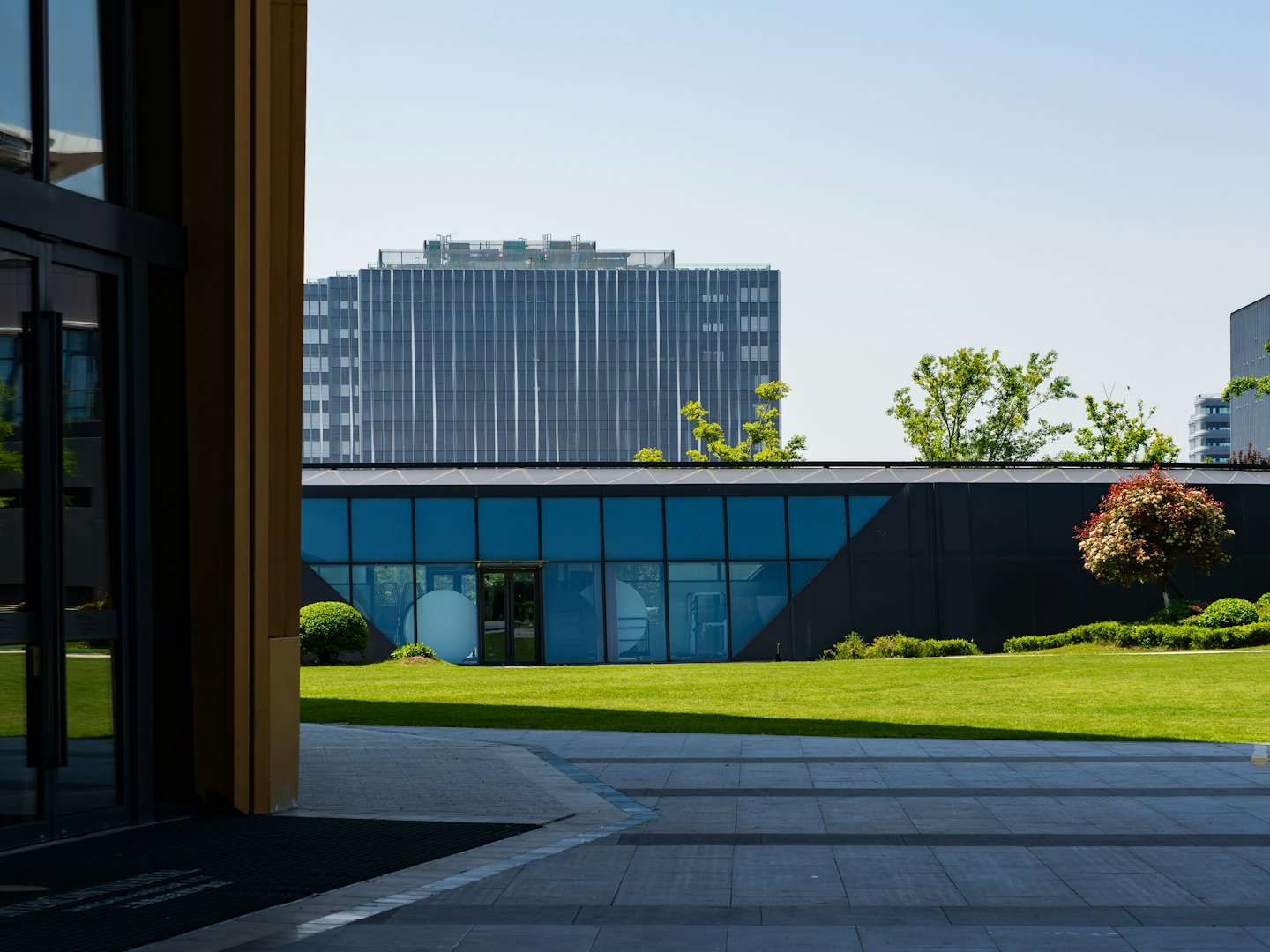Gepflegter Rasen und gepflasterte Wege zwischen modernen Bürogebäuden.